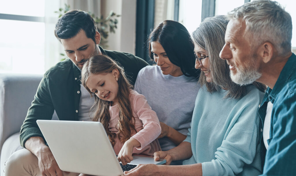 Photo of multiple generation family gathered around laptop