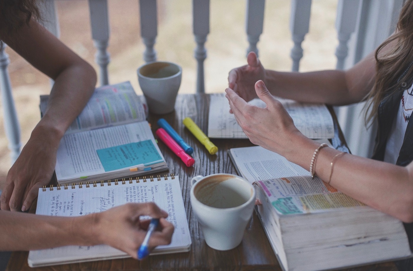 Two girls talking over open bibles at coffee shop.